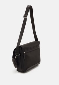 Borsa a tracolla nera caratterizzata da un tessuto morbido e resistente all'acqua, forma rettangolare, tracolla regolabile e tasca frontale con zip.