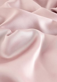 Glat lyserød satin stof med bløde folder og bløde højdepunkter, der skaber en silkeagtig, flydende tekstur.