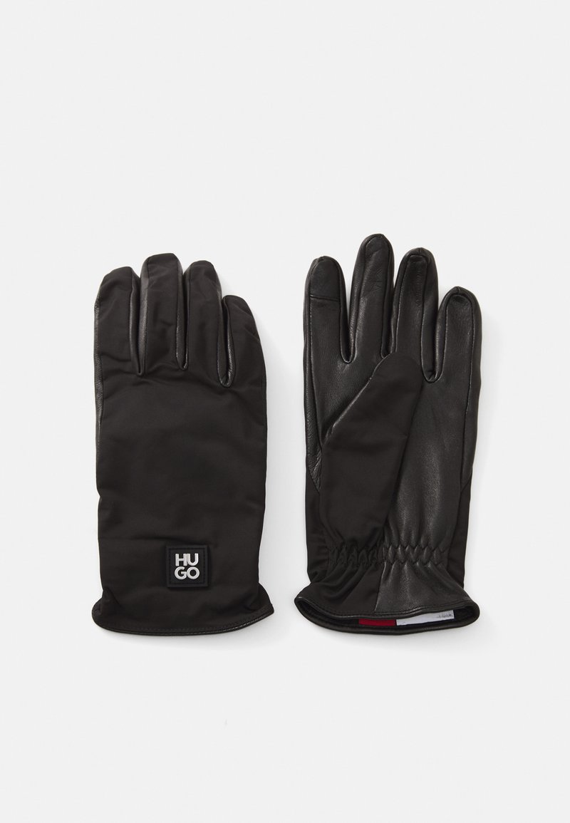 Gants noirs alliant cuir structuré et tissu lisse. Design de poignet froncé avec un petit écusson logo sur le poignet.