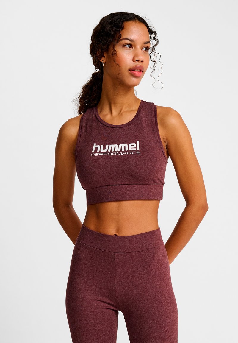 Vinröd sportig kort topp med rund hals och vit "hummel PERFORMANCE"-logotyp. Tillverkad av stretchigt tyg, med tajt passform och slät textur.