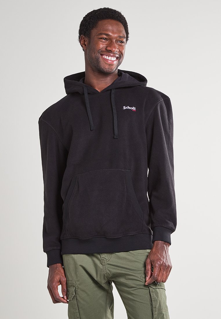 Sweat à capuche en polaire noir avec cordons de serrage, poche kangourou à l'avant et poignets élastiques. Logo rouge sur la poitrine. Porté avec un pantalon cargo olive.