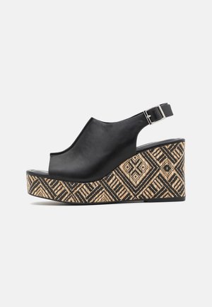 Sandalias de cuña de cuero negro con diseño de punta abierta y talón al aire. La plataforma cuenta con un acento tejido estampado en beige y negro.