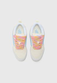 Beige sneakers with light blue accents and textured multi-colored laces. The design features a low-top silhouette and rubber soles.