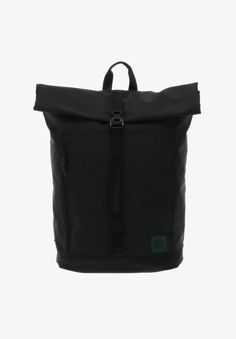 Sac à dos noir à fermeture enroulable avec sangle avant à boucle, poche latérale zippée, poignée de transport sur le dessus et écusson avec le logo Lacoste en bas à droite.
