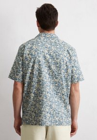Korte mouwen shirt met een blauw en crème abstract bladerenpatroon, gemaakt van lichtgewicht stof met een ontspannen pasvorm en een klassieke kraag.