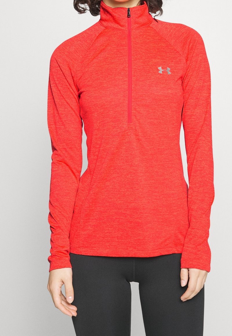 Röd atletisk långärmad tröja med kvartdragkedja, tillverkad av texturerat tyg, med en åtsittande design och grå logotyp på bröstet.