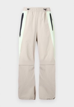 Μπεζ παντελόνια με ανοιχτοπράσινες πλαϊνές φάσες, μαύρες τσέπες μηρών με φερμουάρ και ελαστική μέση με μαύρα κορδόνια.