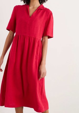 Robe midi rouge à manches courtes, col en V et taille froncée portée par une personne sur un fond clair uni.