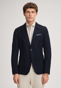 Blazer navy a trama con revers a discrezione, due tasche frontali, chiusura con un bottone e un accento decorativo a forma di fiore sul revers.