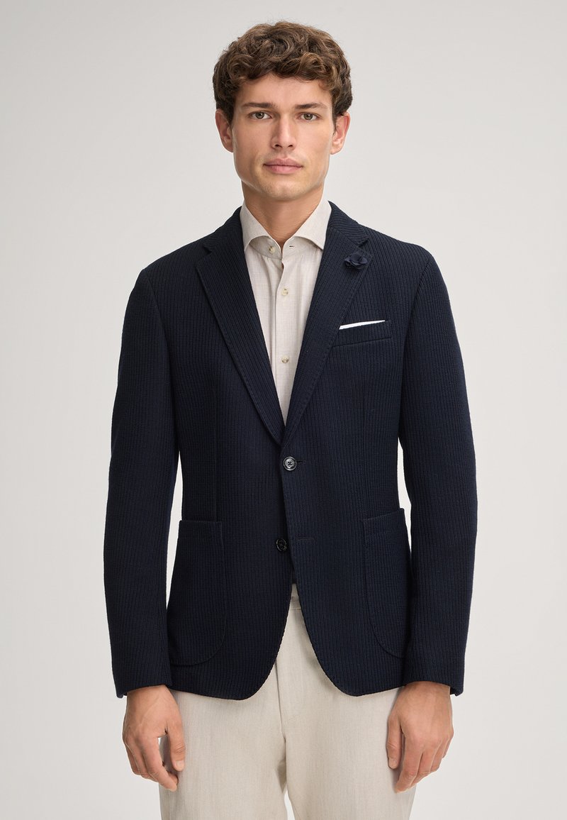 Blazer navy a trama con revers a discrezione, due tasche frontali, chiusura con un bottone e un accento decorativo a forma di fiore sul revers.