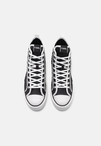 Mustad sneakers musta kanva ja kummist, valgete paeltega, ümmarguse varbaga ja tekstuurse külgkujundusega. "KARL" logo keele peal.