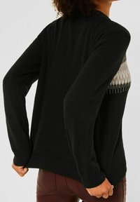Black sweater with long sleeves, featuring a textured design on the upper front. Ribbed cuffs and hem, soft knit material, casual fit.