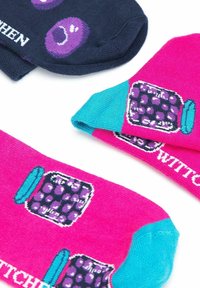 Calcetines coloridos con un diseño en azul marino oscuro con puntos morados y un diseño en rosa brillante con un patrón de tarros, acentuados por una banda turquesa.