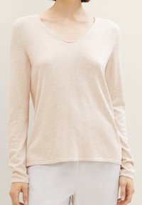 Hellrosa, langärmliger Pullover mit V-Ausschnitt, weichem Textil und entspannter Passform. Mit gerippten Bündchen und einem fertig gearbeiteten Saum.