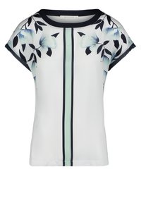 Top de manga corta con estampado floral que presenta una base blanca con flores azules, una raya vertical verde y un cuello azul marino. Textura de tela suave.