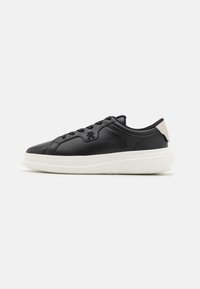 Czarne skórzane sneakersy o gładkim wykończeniu, z białą podeszwą środkową i miękkim beżowym akcentem na pięcie. Związane konstrukcje z teksturowanymi bokami.