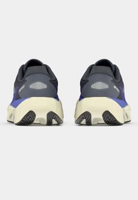 Αθλητικά παπούτσια με σκούρο γκρι επάνω μέρος, μοβ λεπτομέρειες και κρεμ ενδιάμεση σόλα· διαθέτουν υφασμένη εξωτερική σόλα για καλύτερη πρόσφυση και υποστήριξη.