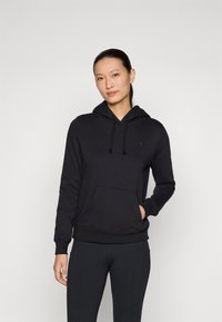 Svart hoodie i mjukt material med känguruficka, dragsko i huvan och en subtil logotyp på bröstet. Stilen har en figurnära silhuett.