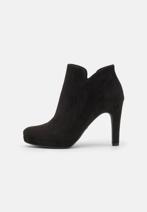 Black suede ankle boots with a rounded toe, high stiletto heel, and side cutouts for a sleek, modern design.