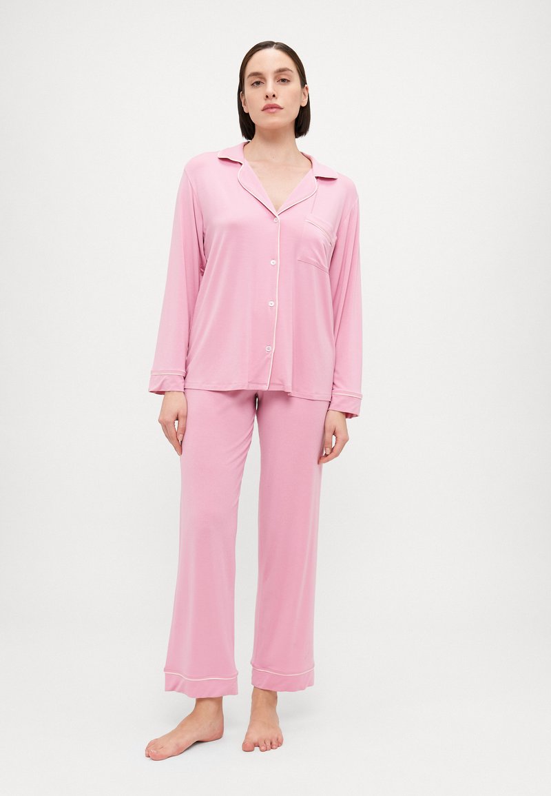 Pink long-sleeve pajama set features a button-down top with a pocket and matching pants, both made from soft, lightweight fabric.