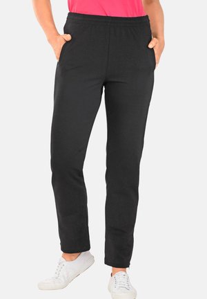 Pantalons de survêtement noirs en tissu doux, dotés d'une taille élastique, de poches latérales et d'une coupe fuselée. Portés avec des baskets blanches.