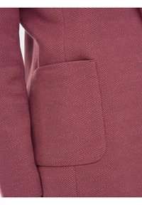 Blazer bordeaux à motif chevron, avec un tissu texturé et une poche latérale. Présente une coupe ajustée et des lignes épurées.