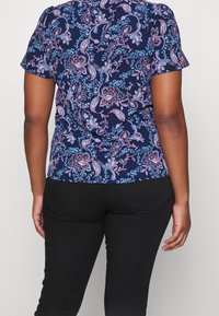 Blusa navy a maniche corte con motivo floreale paisley in rosa e azzurro chiaro. Realizzata in tessuto leggero con orlo curvato.