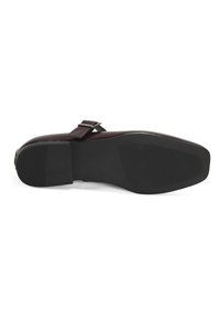 Schwarzer flacher Schuh mit einer strukturierten Gummisohle, runder Zehenform und einem verstellbaren Riemen mit einer silbernen Schnalle. Obermaterial aus glattem Leder.