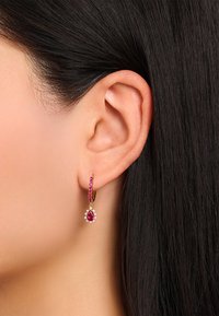 Goldene Creolen mit pinkfarbenen Edelsteinen und einem birnenförmigen roten Stein am Boden, ausgestattet mit einem floralen Design aus kleinen klaren Akzenten.