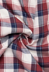 Tessuto a quadri rossi e blu navy con sfondo bianco, caratterizzato da schemi intrecciati stretti e una superficie liscia, leggermente stropicciata.
