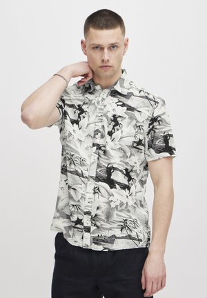 Korte mouw blouse met een zwart-wit tropisch patroon, met palmbladeren en silhouetten; blouse met knopen in een lichte, gestructureerde stof.