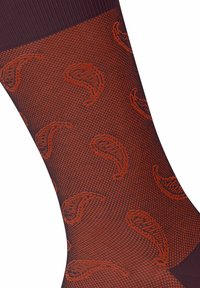 Chaussettes bordeaux avec un motif texturé de formes abstraites rouges. Fabriquées dans un matériau extensible, elles possèdent un bord-côte en haut pour un bon maintien.