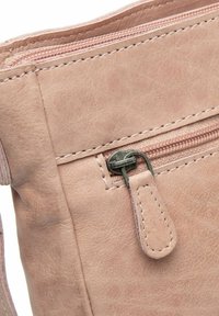 Primo piano di una borsa in pelle rosa, con una tasca con zip, texture liscia, cuciture in contrasto e un dettaglio di tirazip in metallo.