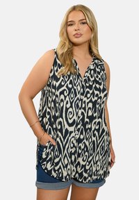 Ärmelloses Hemd in Marineblau und Creme mit einem abstrakten Muster, ausgestattet mit einer Knopfleiste vorne und Seitentaschen, hergestellt aus leichtem Stoff.