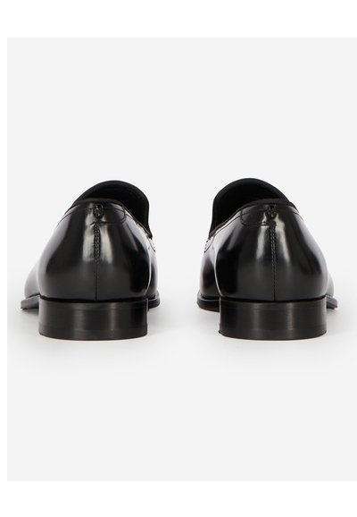 Paire de chaussures habillées en cuir noir poli vues de dos sur un fond blanc.