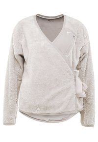 Jasno beżowa polarowa kurtka z długimi rękawami, diagonalną kieszenią na zamek i bocznym wiązaniem.