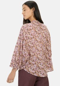 Blomstret bluse i nuancer af lilla, orange og brun, med en rund halsudskæring, løs pasform og lange puffede ærmer.