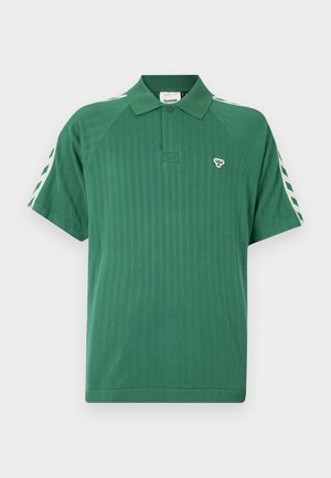 Grünes Poloshirt aus geripptem Stoff, mit Kragen, kurzen Ärmeln und kontrastierenden diagonalen Streifen auf den Schultern. Kleines Logo auf der Brust.