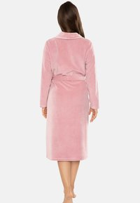 Robe rosa di lunghezza media in morbido tessuto peluche. Caratterizzato da un colletto a scialle e una cintura regolabile. Maniche lunghe e colore uniforme senza fantasie.