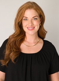 Gouden golfvormige ketting gedragen over een zwarte top met een verzamelde halslijn. De top heeft korte mouwen en een vierkante kraag.