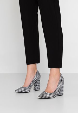 Chaussures à talons hauts à motif vichy noir et blanc, avec un bout pointu et un talon épais, fabriquées en matériau texturé.