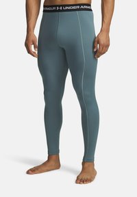 Miestne slim-fit legíny Under Armour v textúrovanej, tlmenej teal farbe s čiernym elastickým pásom, na ktorom je logo značky.