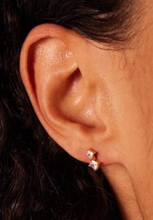 Boucles d'oreilles en plaqué or avec deux pierres transparentes taillées en carré, une plus grande et une plus petite, dans un design minimaliste.