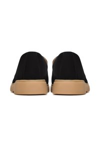 Czarne buty wsuwane o gładkiej cholewce i beżowych gumowych podeszwach, o zaokrąglonym kształcie i minimalnych detalach w szwach.