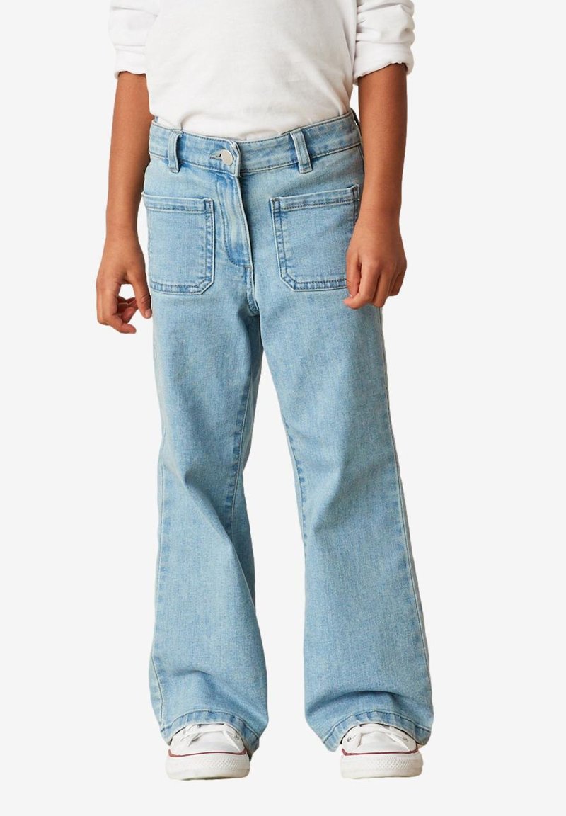 Jeans din denim de culoare albastru deschis, cu o croială confortabilă, dotate cu două buzunare spate și fermoar. Terminată cu tivuri răsucite și adidași albi.
