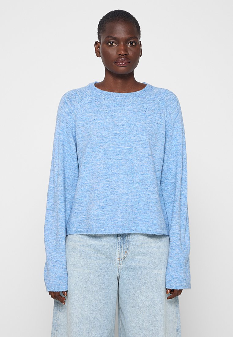 Hellblauer Pullover mit strukturiertem Gestrick, Rundhalsausschnitt und langen Ärmeln, kombiniert mit hellen Jeans. Weiches, lässiges Design.