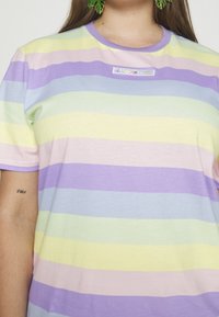 T-shirt rayé multicolore dans des teintes pastel de jaune, lavande et vert. Doté d'un col rond et d'un petit patch de marque.