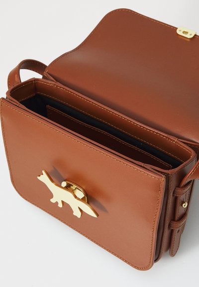 Borsa in pelle marrone con una chiusura a forma di volpe dorata. Presenta un design piatto, una forma strutturata e un interiore nero a contrasto. Compatta e funzionale.