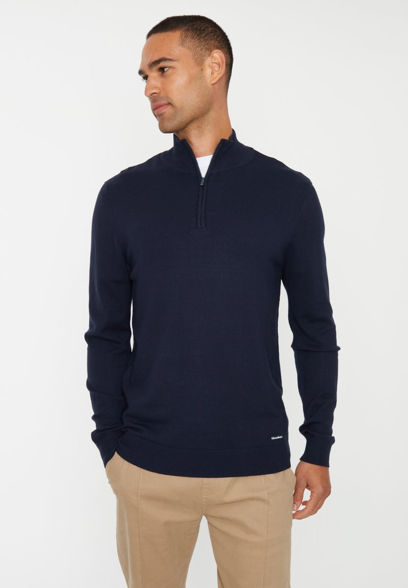 Maglione blu navy a manica lunga con zip a un quarto, in tessuto lavorato a maglia, e con polsini e orlo a costine. Presenta un piccolo etichetta del marchio in fondo.