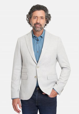 Blazer gris claro con dos bolsillos frontales y botones dorados, usado sobre una camiseta de botones a cuadros azules, combinado con jeans oscuros.